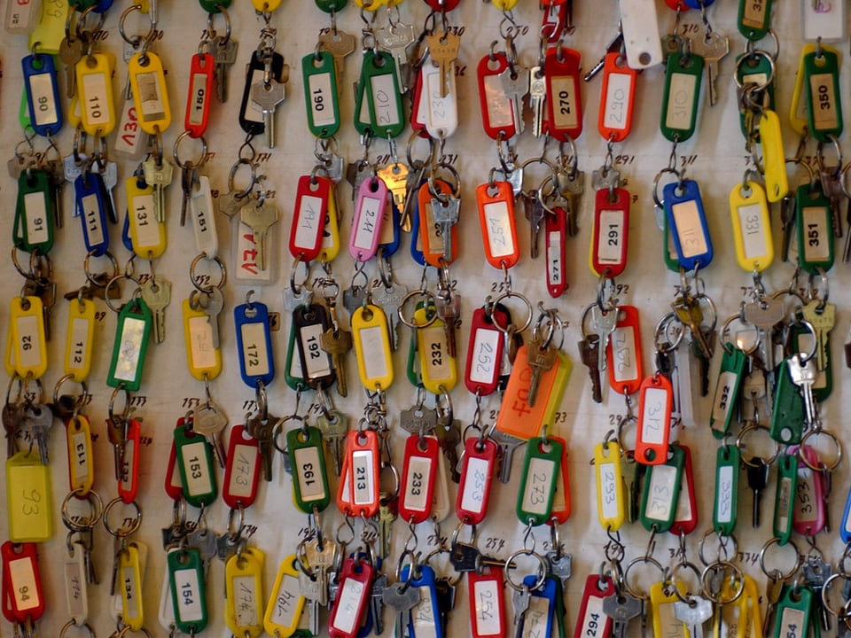 Viele Schlüssel mit bunten Schildern an einem Schlüsselbrett.
