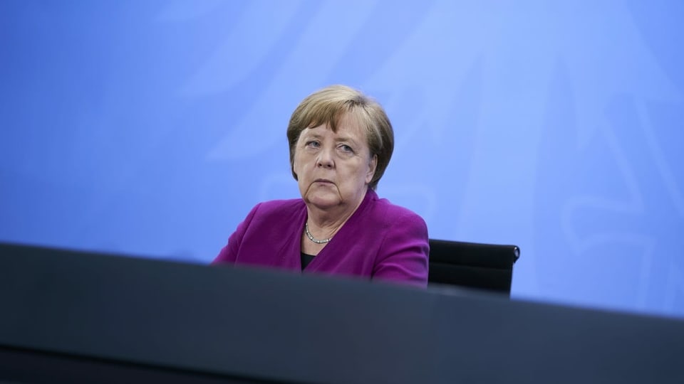 Merkel sitzt an einem Tisch.