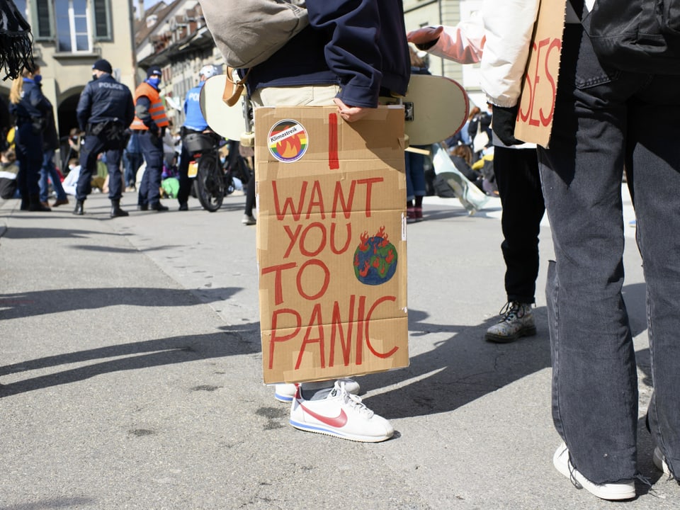 Demonstrierende Person trägt ein Schild. Darauf steht: I want you to panic. 