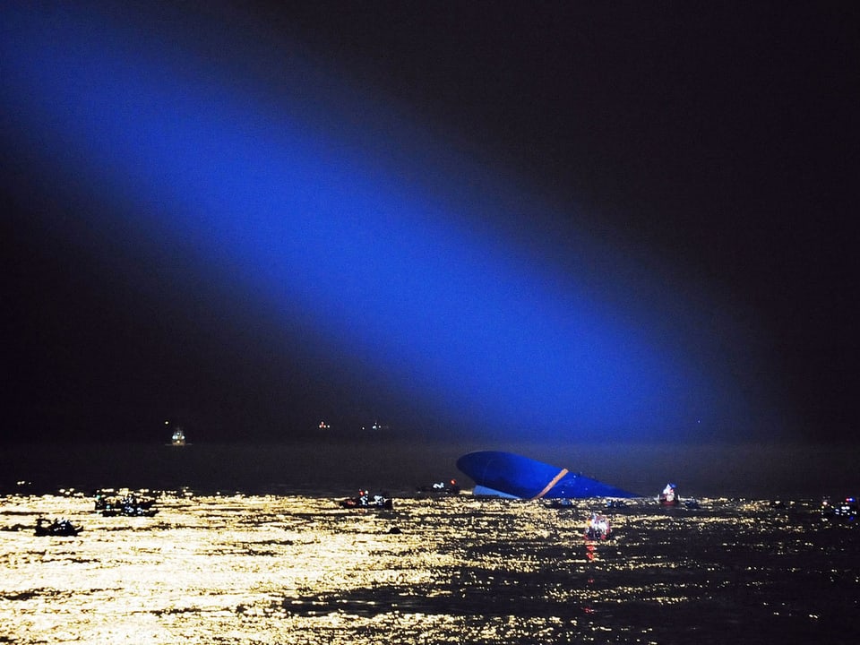 Helikopter suchen die Wasseroberfläche mit blauem Scheinwerferlicht ab.