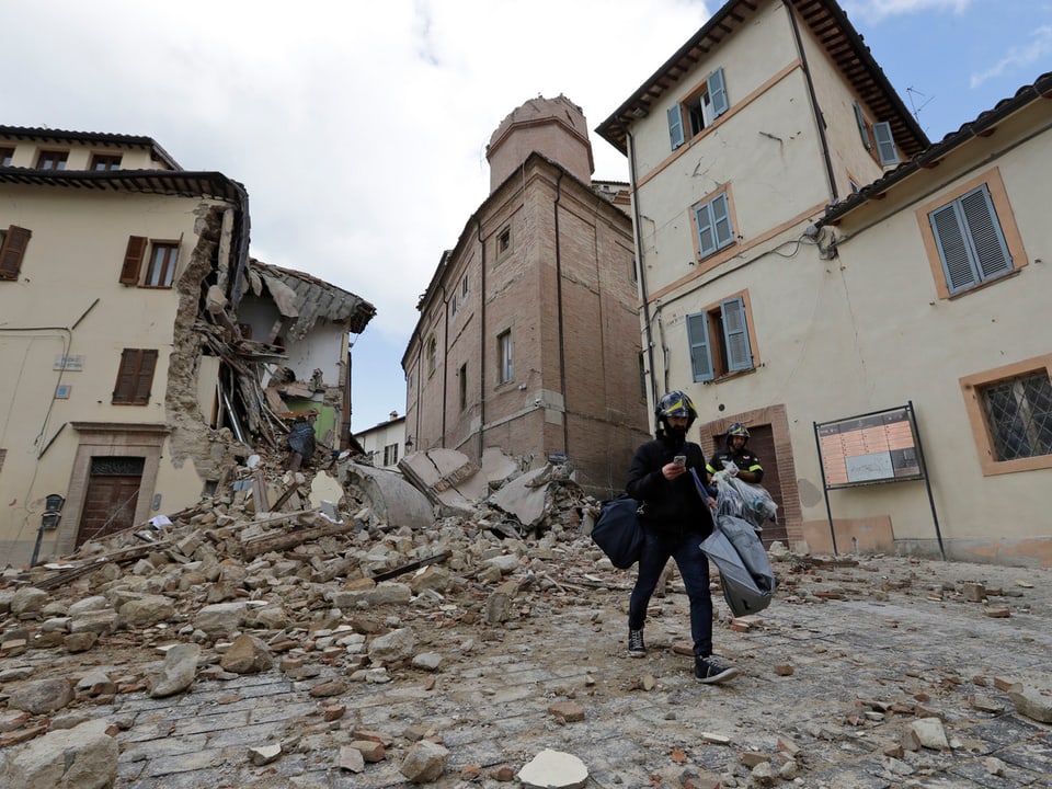 Ein Mann trägt seine Habe aus der zerstörten Stadt Camerino