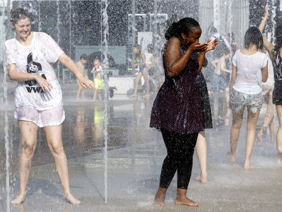 Mädchen kühlen sich bei einem Springbrunnen ab