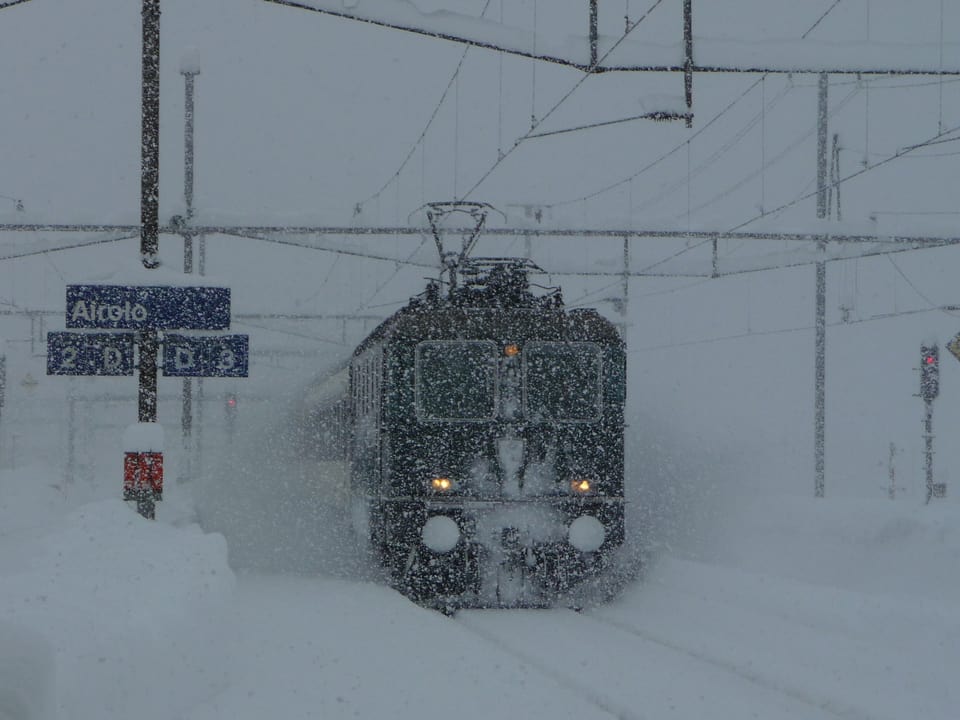 Eine Lokomotive fährt durch den tiefverschneiten Bahnhof in Airolo.
