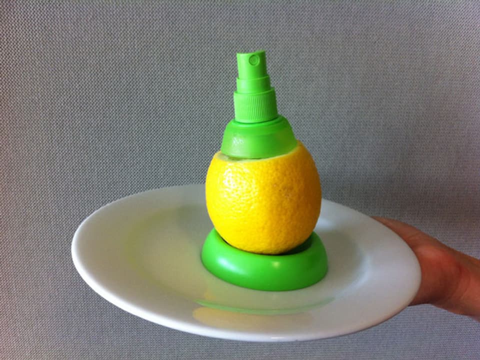 Zitrone mit aufgesetztem Sprühkopf steht auf dem Untersatz