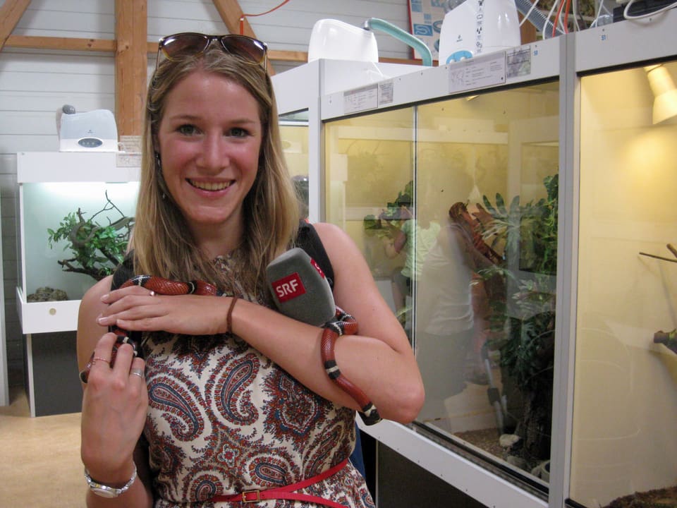 Regionaljournal-Reporterin Rebecca Dütschler hält eine rot-schwar-weiss gestreifte Schlange.