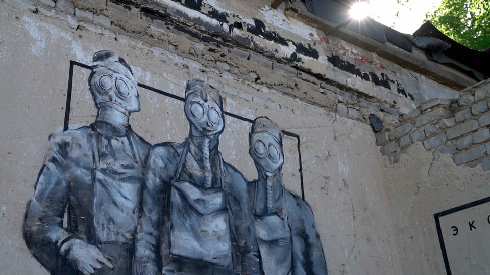 Wandgraffiti mit drei Personen in Gasmasken