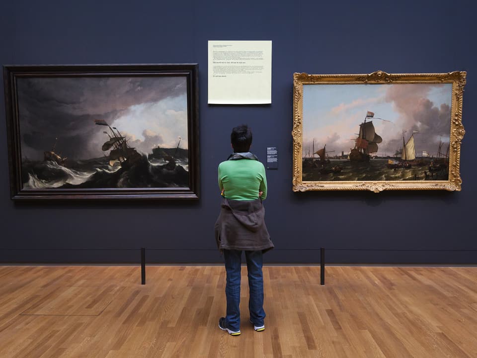 Ein Besucher schaut sich zwei Gemälde an. In der Mitte ist ein Post-It.