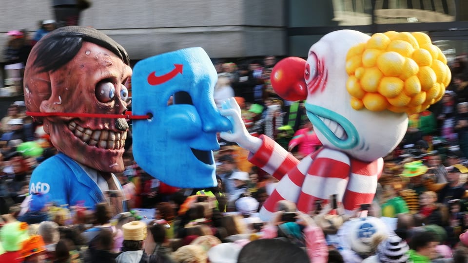 Ein Clown zieht einem Totenkopf die Maske vom Gesicht. 