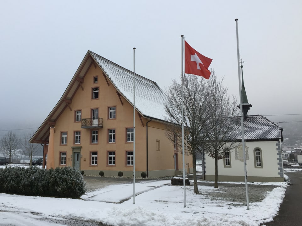 Historisches Wohngebäude, daneben eine Kapelle, davor eine Schweizerfahne