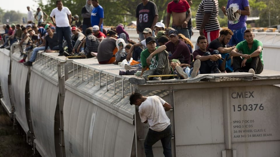 Dutzende Menschen sitzen auf einem Zugdach in Zentralamerika.