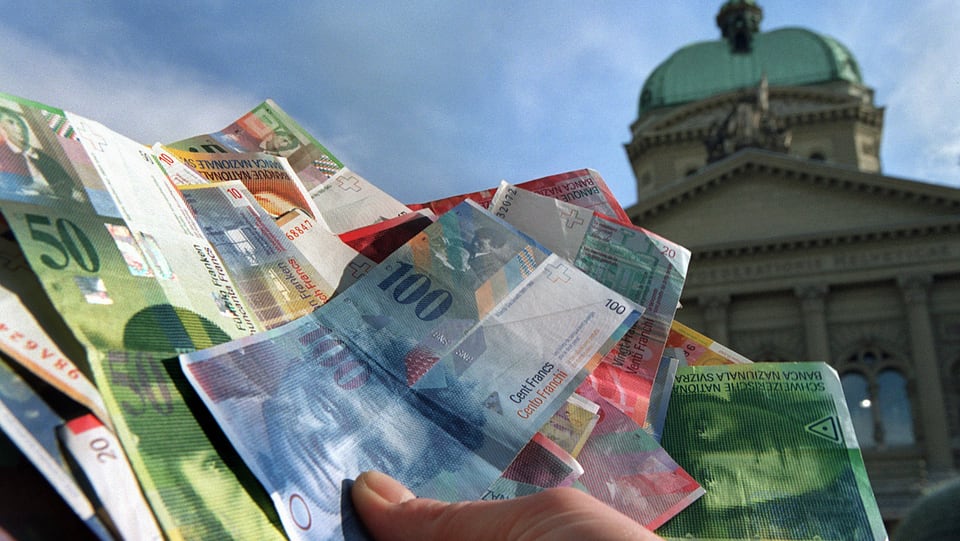 Mann hält Banknoten vor Bundeshaus.
