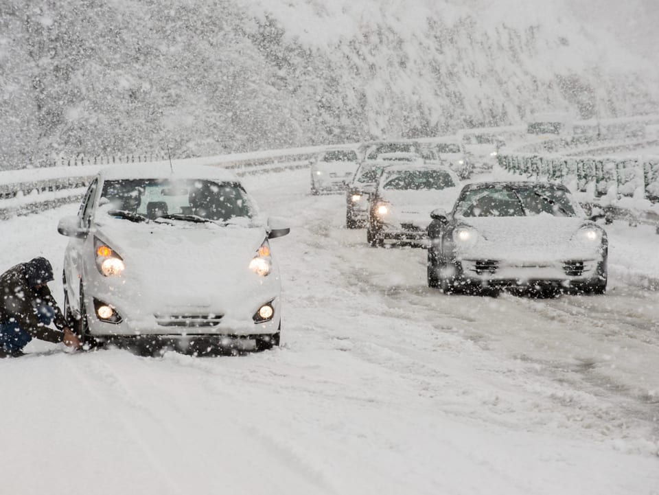 Ein Autofahrer montiert Schneeketten auf der Autobahn A2 auf dem Monte Ceneri Richtung Norden,.