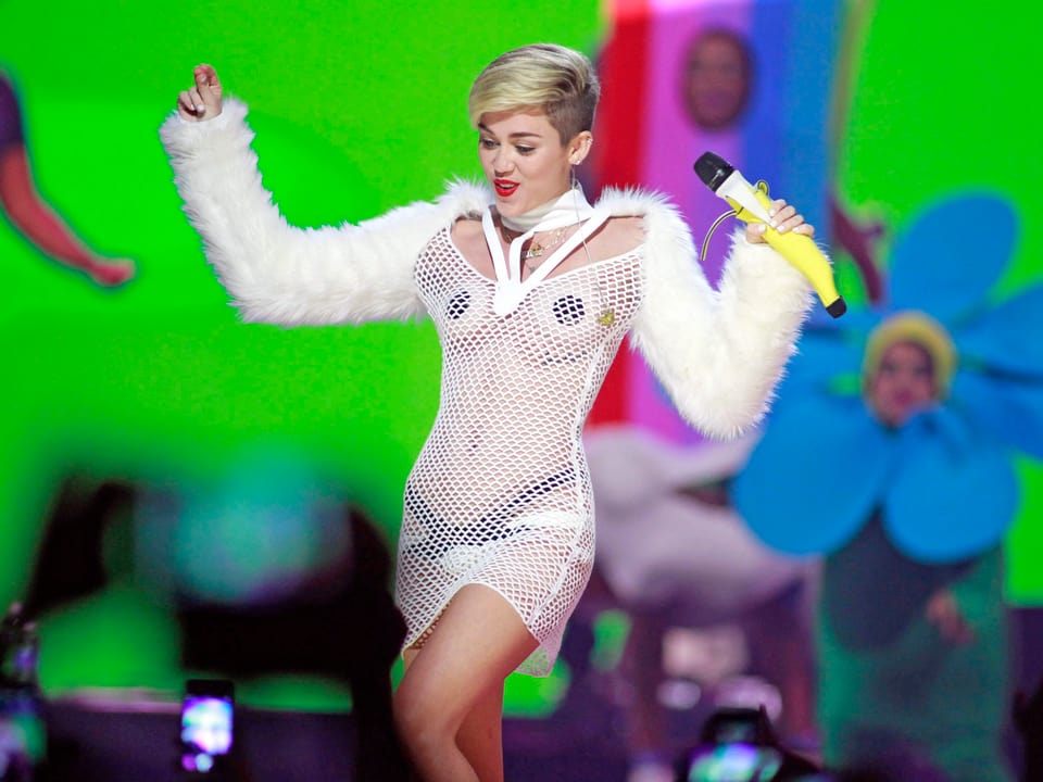 Miley Cyrus in Netzkleid und Plüsch-Jäckchen.