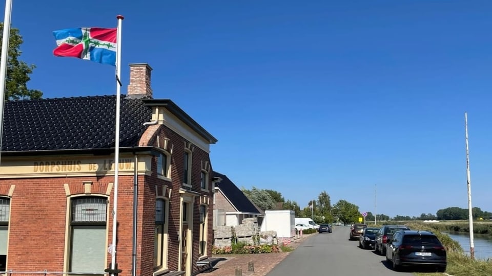 Das Dorpshuis von Garmerwolde Haus mit Fahne neben Kanal