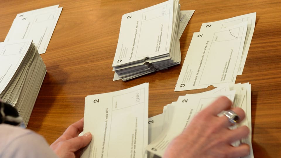 Eine Frau sortiert Stimmzettel der eidgenössischen Abstimmung nach Vorlage.