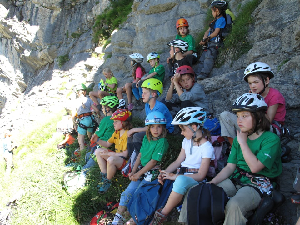 Gruppe von Kindern eines Kletterlagers, die im Schatten sitzen. 
