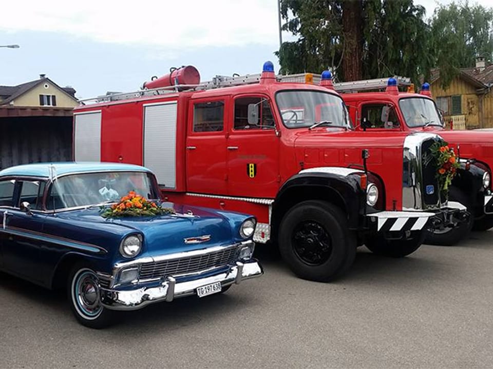 Bild eines für Hochzeit geschmücktes Auto neben Feuerwehr-Autos
