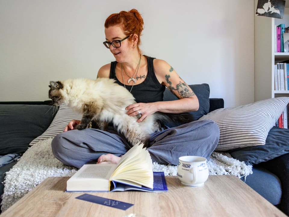 Fränzi Gall zu Hause mit einem Buch, einer Tasse Kaffee und ihrer Katze.