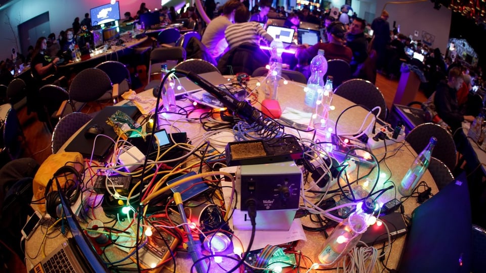 Tisch am CCC-Kongress: Computer und viele Kabel, bunt beleuchtet.