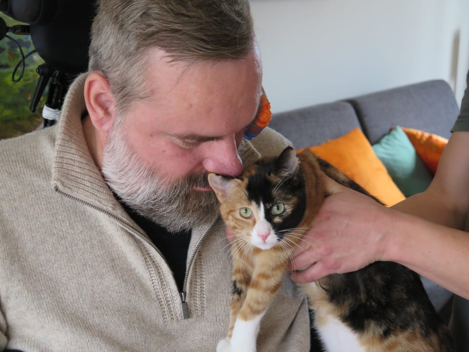 Stefan Csombo hält den Kopf an seine Katze.