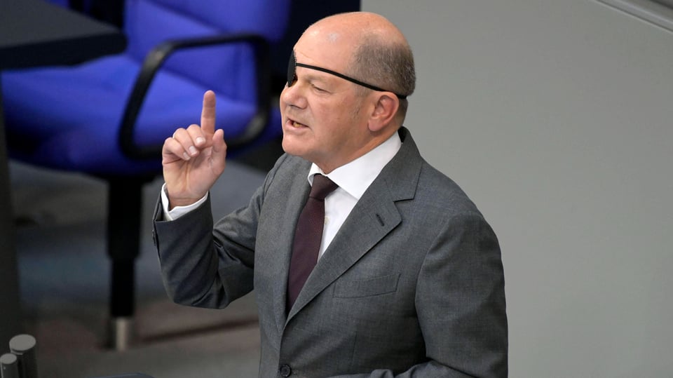 Olaf Scholz spricht vom Rednerpult im Bundestag und hält den rechten Zeigefinger hoch