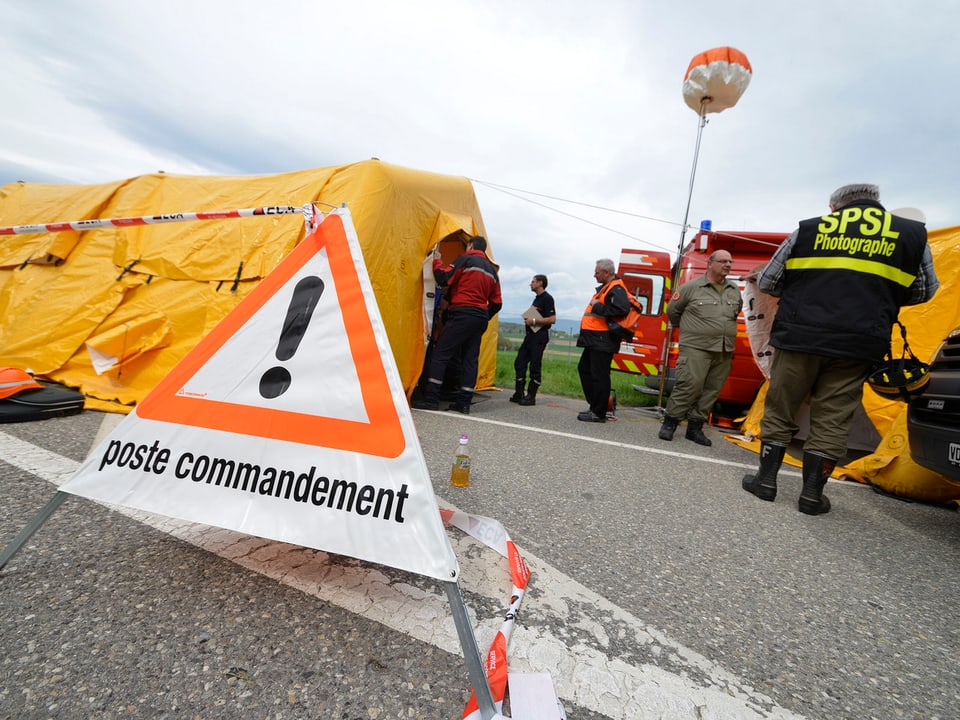 Verkehrsdreieck mit der Aufschrift "Poste commandement", im Hintergrund das gelbe Zelt des Kommandopostens der Einsatzkräfte