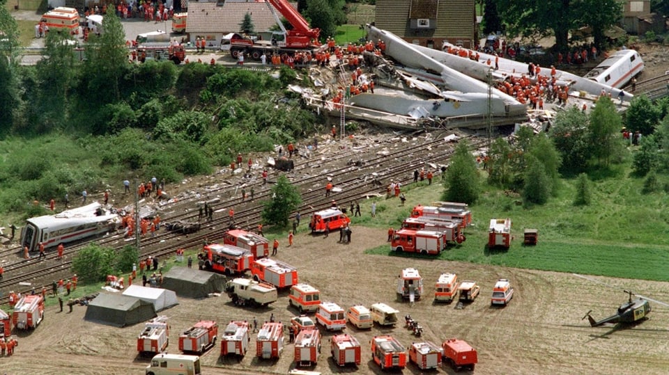 The wreckage of the crashed Intercity-Express ICE 884 lies in front of a detached house along the railroad tracks.