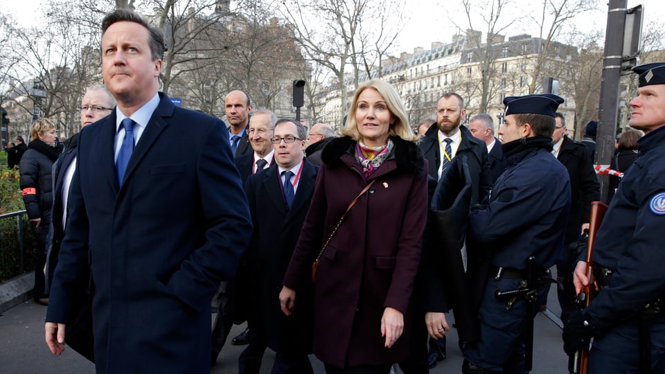David Cameron (vorne Links) vor einer Personengruppe gehend, auf der rechten Seite stehen Polizisten.