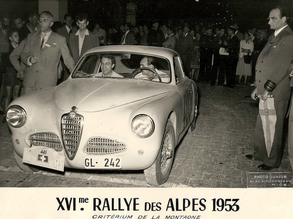 Ein Auto in Schwarzweiss mit Rennfahrer Harry Zweifel am Steuer. 