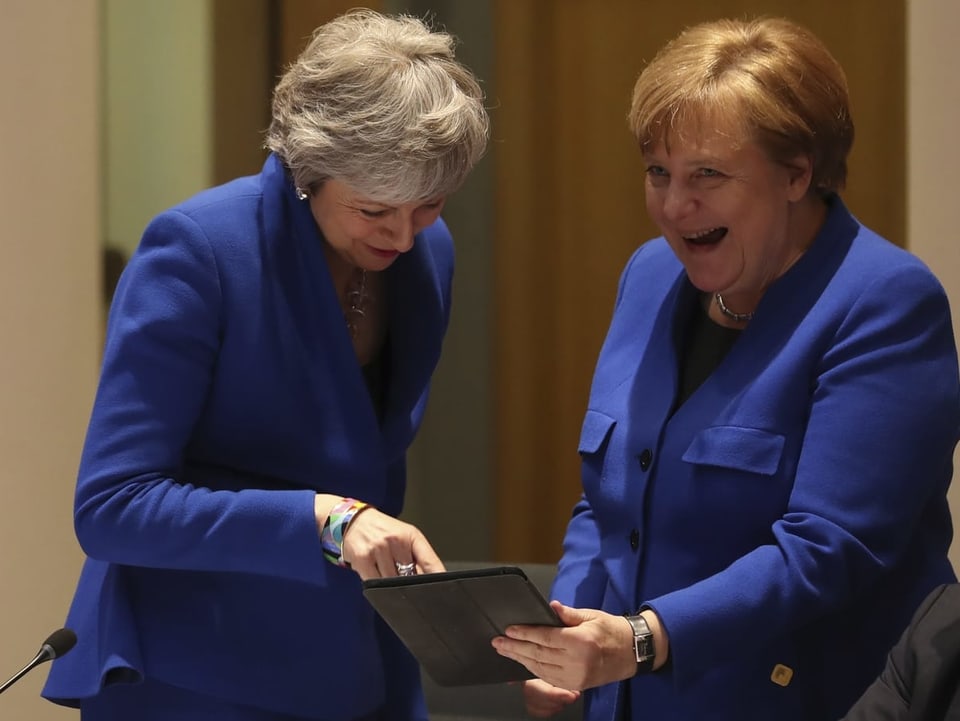 Merkel zeigt May eine Karrikatur auf dem Tablet. 