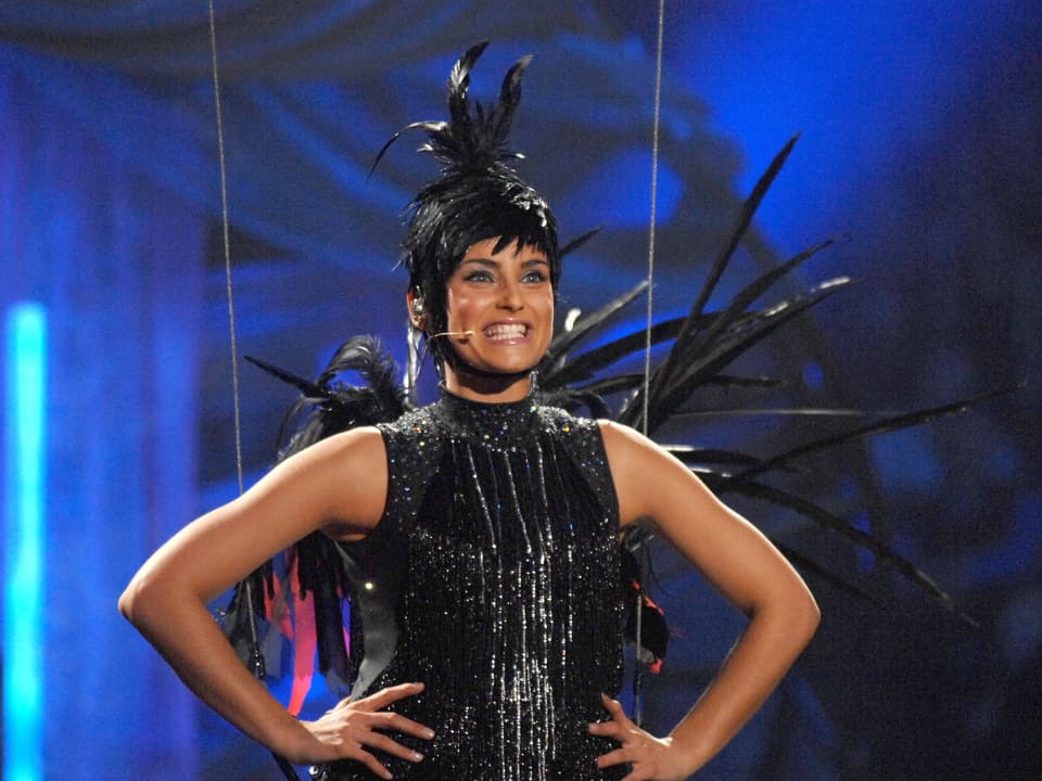 Nelly Furtado lachend in Schwarzem Vogelkostüm auf der Bühne