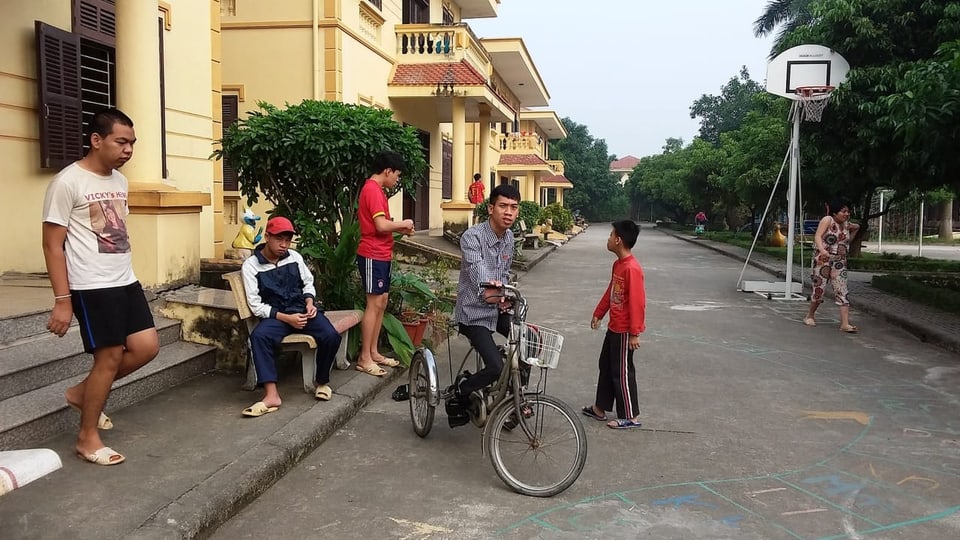Blick auf eine Quartierstrasse mit einzelnen Menschen in Hanoi