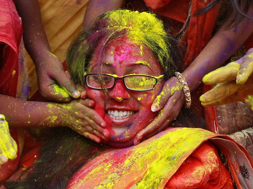 Eine junge Frau lässt sich von verschiedenen Händen die Farben auftragen.