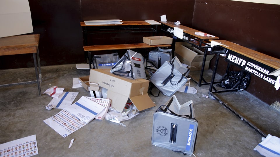 Urnen und Wahlzettel liegen in einem Wahllokal am Boden 
