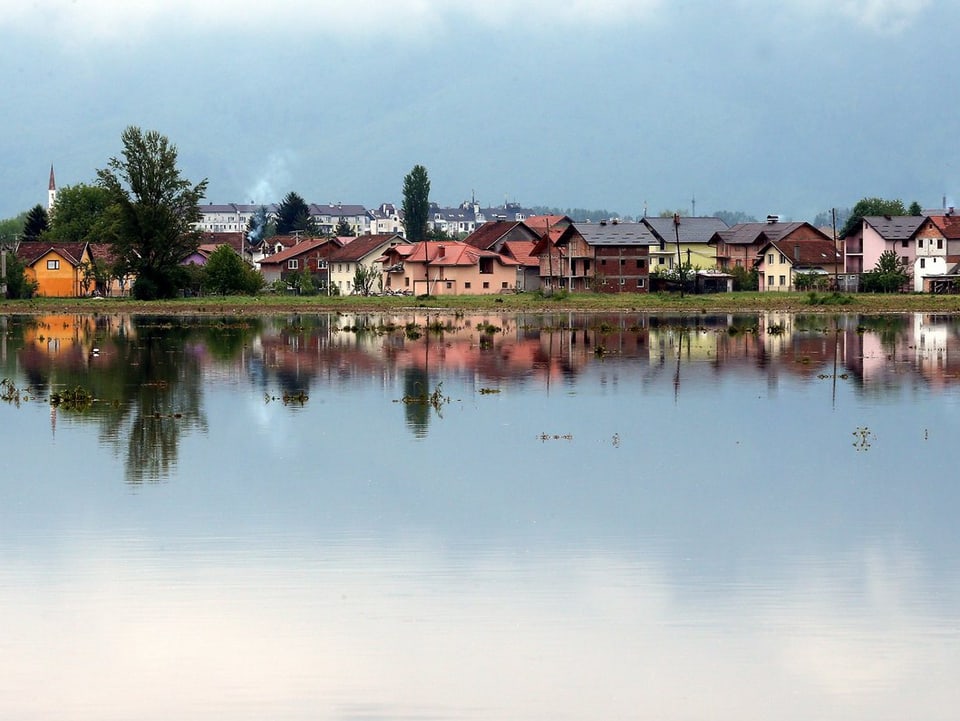 Ein Dorf vor einer überschwemmten Wiese.