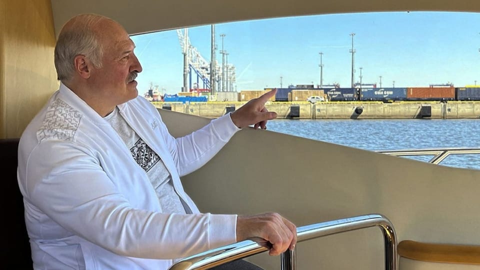 Der belarussische Machthaber Alexander Lukaschenko zeigt auf Container am Hafen von einem Schiff aus.