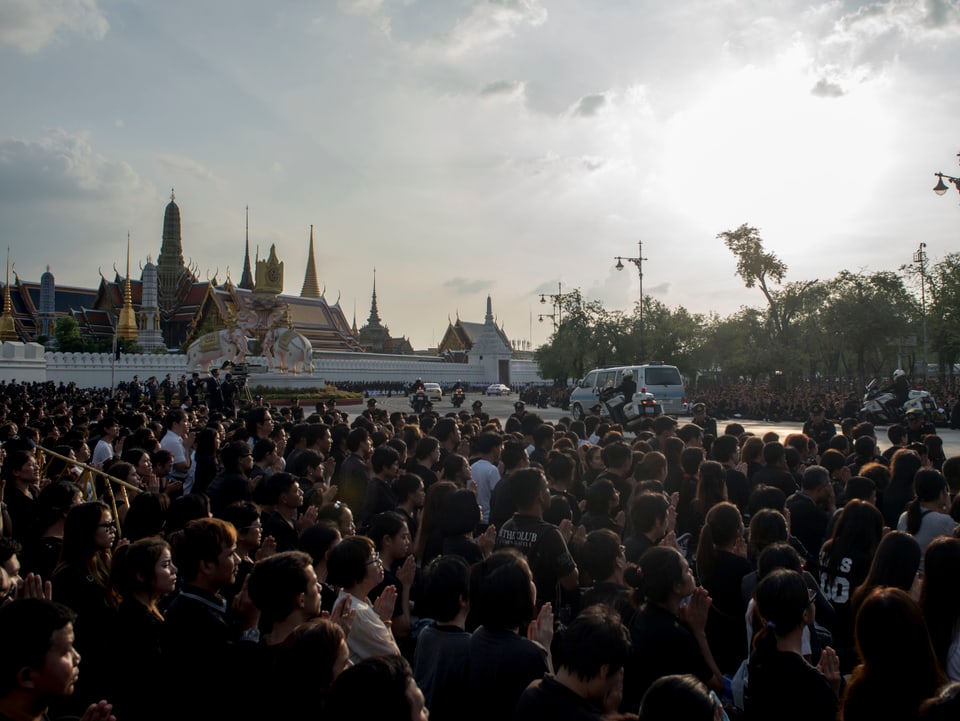 König Bhumibol wird in den Palast überführt – Zehntausende Thais knien am Wegrand nieder und beten.