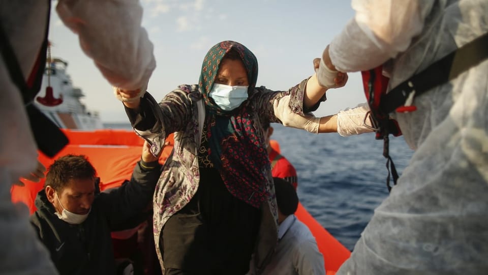 Eine Frau steigt von einem Schlauchboot auf ein Schiff um