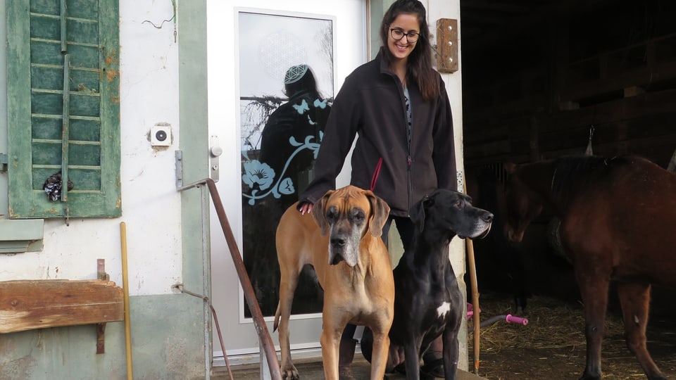 2 Hunde und eine Frau stehen vor einer Haustür