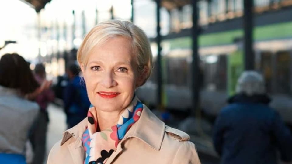 Portrait einer Frau vor Zügen im Bahnhof.