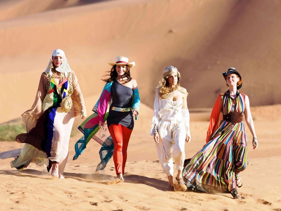 Vier modisch gekleidete Frauen in der Wüste.