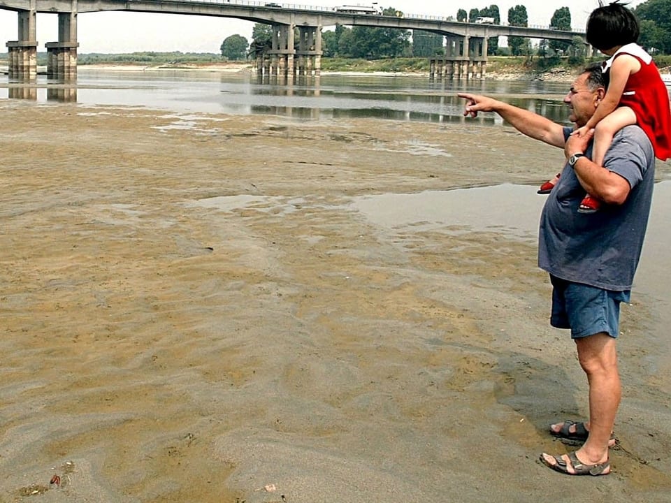Grossvater mit Kind auf den Schultern wandert durch das trocken Flussbett, Juni 2003 Fluss Po.