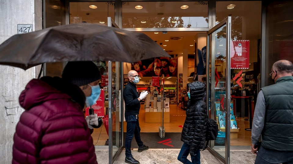 Menschen mit Masken vor einem italienischen Buchladen.