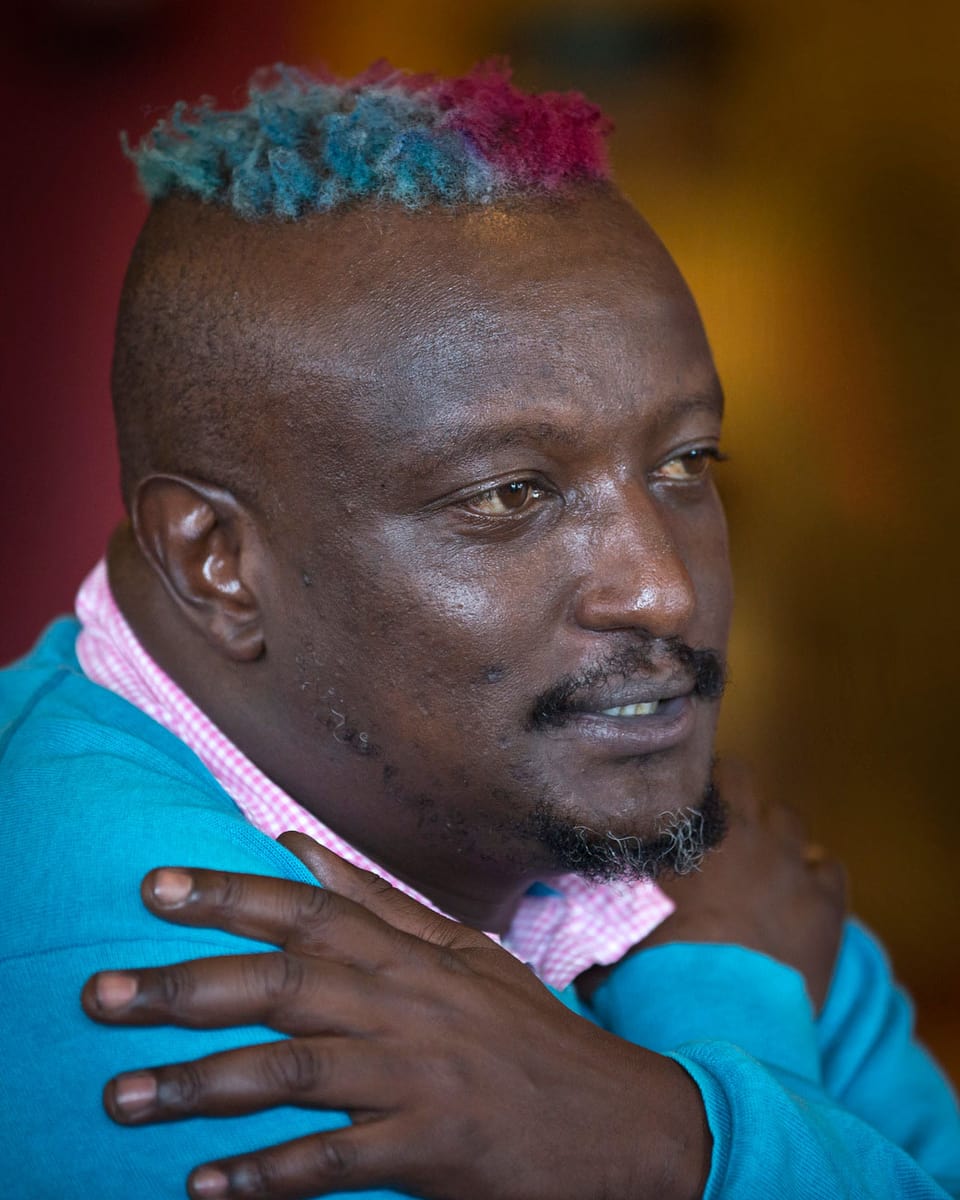 Porträt von der Seite. Binyavanga Wainaina hält die Arme über der Brust gekreuzt und spricht.