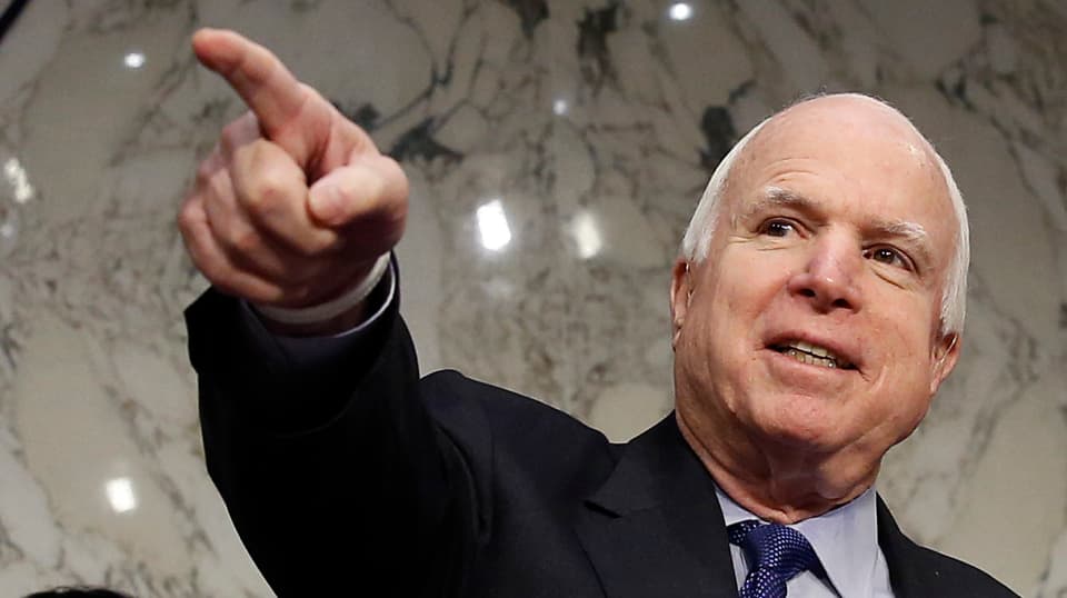 John McCain zeigt mit ausgestrecktem Arm in die Ferne. 