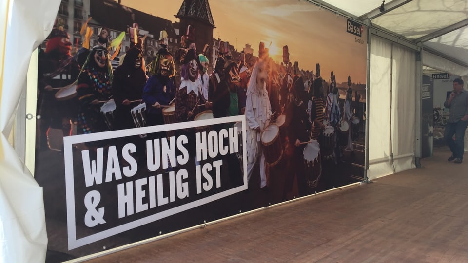 Ein grossformatiges Plakat mit einem Foto der Basler Fasnacht und dem Spruch: Was uns hoch & heilig ist.