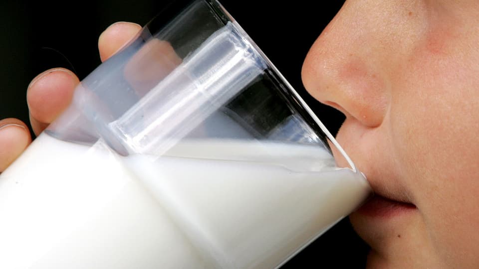 Ein Junge trinkt ein Glas Milch.