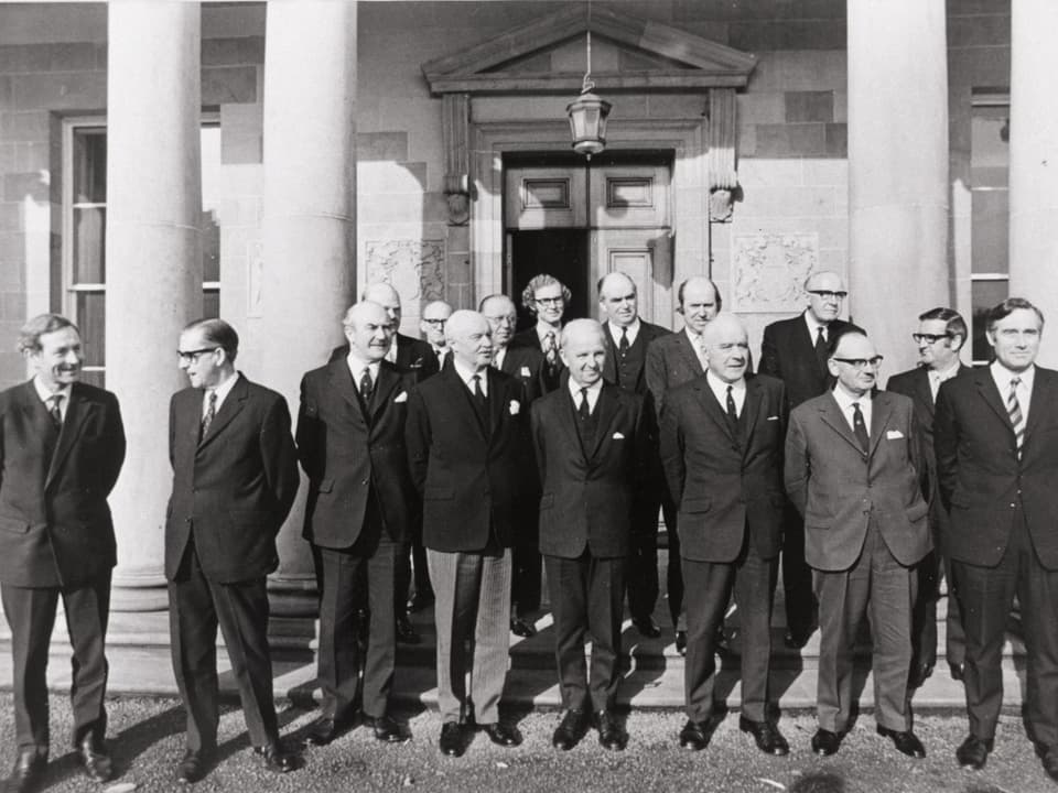 Männer der Regierung vor einem Gebäude.