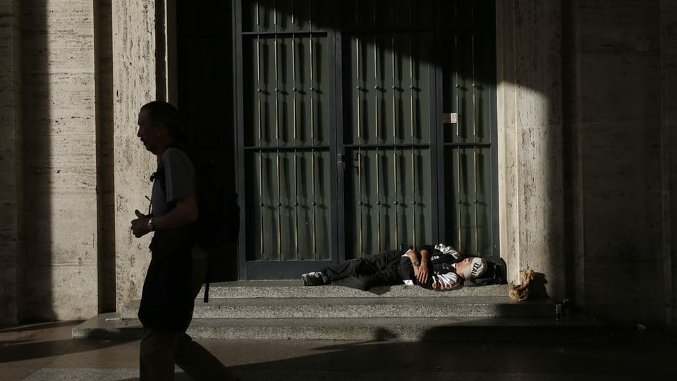 Obdachsloser schläft an Mauer.