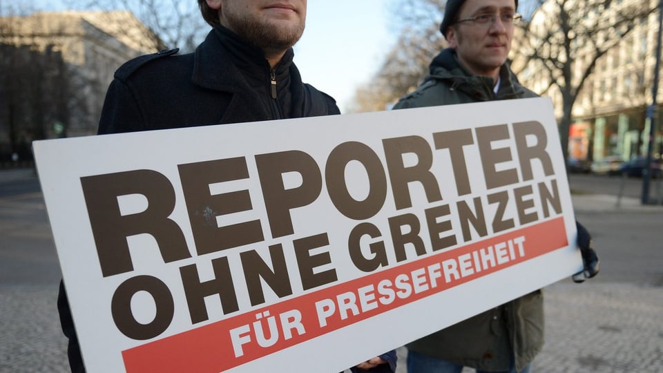Zwei Männer halten ein Schild von Reporter ohne Grenzen.